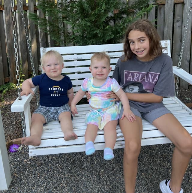  Three children sitting on a white bench